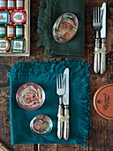 Messer und Gabeln mit Servietten und Käseauswahl auf hölzernem Esstisch in London home England UK