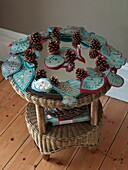Decorative handmade leaves with pinecones on wicker side table in London home England UK