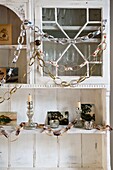 Paper chains with silver candlesticks on painted dresser in London home England UK