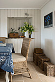 Wicker chair and baskets at dining table with blue tablecloth in Penzance farmhouse Cornwall England UK
