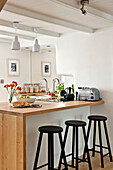 Black stools at breakfast bar in open plan kitchen of family townhouse Cornwall England UK