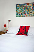 Kunstwerk über einem Doppelbett mit Seitenlampen und Kissen mit religiösem Symbol im Schlafzimmer eines Stadthauses in Cornwall England UK