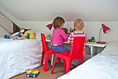 Kleinkinder spielen im Schlafzimmer eines Familienhauses in Cornwall England UK