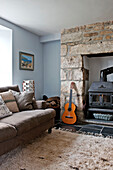 Guitar beside woodburning stove in living room of holiday cottage Cornwall UK