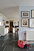 Footwear and artwork with spade and bag in flagstone hallway of holiday cottage Cornwall UK