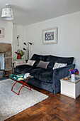 Blue velvet two-seater sofa in living room with parquet floor in Cornwall cottage UK