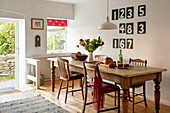 Wooden dining table with scoreboard numbers and open back door in Cornwall cottage UK