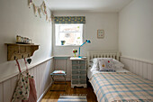 Stecktafel und Wimpel mit Einzelbett und Nachttisch in einem Kinderzimmer in Cornwall, Großbritannien