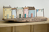 Row of hand painted houses with nails for chimneys on driftwood Cornwall UK