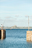Angler steht mit Angelrute an einer Hafenmauer in Cornwall UK