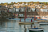 Moored boats in harbour with seafront promenade Cornwall UK