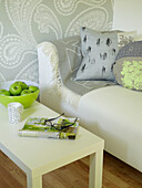 Fresh apples on coffee table with sofa and paisley wallpaper in UK summerhouse