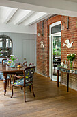 Wooden dining table and chairs with architectural mirror and exposed brick wall in Tunbridge Wells home Kent England UK