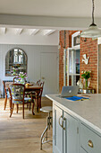 Wooden dining table and chairs with architectural mirror and exposed brick wall in Tunbridge Wells home Kent England UK