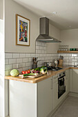Fresh vegetables on wooden worktop with stainless steel extractor in tiled St Ives kitchen Cornwall UK