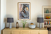 Pair of grey lamps with modern art and vases on sideboard in St Ives home Cornwall UK