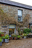 Gardening barrow on gravel driveway at window of Penzance home Cornwall UK