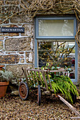 Gardening barrow on gravel driveway at window of Penzance home Cornwall UK