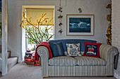Striped sofa with blue blanket below framed artwork with Christmas decorations in Penzance farmhouse Cornwall UK