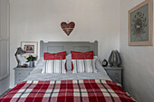 Heart shaped stars and strips above red and white checked blanket on grey double bed in Penzance farmhouse Cornwall UK