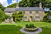 Freistehendes Bauernhaus aus Stein mit Wasserspiel im Rasen in Helston Cornwall UK