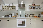 Cream fitted kitchen with shelf storage for crockery in Marazion beach house Cornwall UK