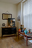 Vases and books on table with sideboard and closed net curtains in London home UK