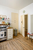 Oven and cupboard storage with metal bin in wood floored retro style London kitchen UK