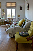 Tapestry cushion on yellow chair with cream sofa in London apartment UK