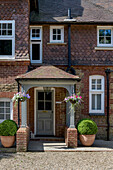 Hanging baskets on entrance porch of Lutyens-style Grade II-listed Victorian property built c1880s in Godalming Surrey UK