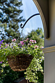 Flowering geraniums in hanging basket on porch of grade II-listed Victorian home Godalming Surrey UK
