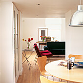 Blick von der offenen Wohnküche in den Wohnbereich mit roten und blauen Polstermöbeln und einem Esstisch mit Kaffeemaschine