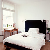 Bedroom with white duvet and pillows and bedside lights 