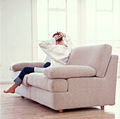 Frau entspannt sich auf dem Sofa im Wohnzimmer und richtet ihr Haar