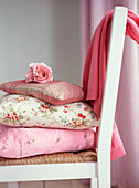 Hübsche Kissen mit Rosenmuster auf weißem Stuhl