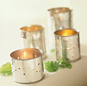 Display of recycled pierced tin can holders with burning candles