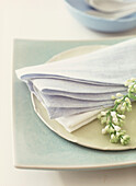 Place setting with crackle glazed turquoise square plate linen napkins and white flower sprig