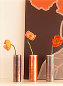 Canvas behind poppies in vases