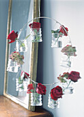 Red roses in glass jars hanging in a wire mobile