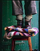 Girl standing on footstool in unlaced boots and thick socks