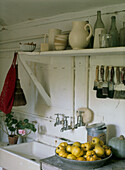 Traditionelle Butler-Spüle im Hauswirtschaftsraum mit Quittenschale und offenen Regalen