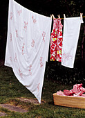 Auf einer Leine im Garten hängende Wäsche mit Wäschekorb
