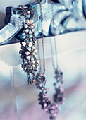 Decorative costume jewellery hanging over a Venetian mirror in the bedroom