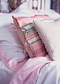 Close up of pretty fabric cushions on pastel coloured bed 