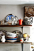 Reclaimed wooden shelves are staked with a mismatched assortment of crockery from plain white pieces to mad swirly patterns