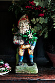 Garden gnome with star flower and Christmas berries in Shropshire cottage England UK