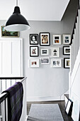 Picture wall and striped floor rug in staircase landing of Lyme Regis home Dorset UK