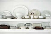 White chinaware and wooden plates on shelves in Lyme Regis kitchen Dorset UK