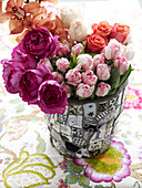 Schnittblumen in gefliester Vase auf geblümter Tischdecke