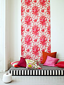 Floral panel above black and white floor mattress with red cushions